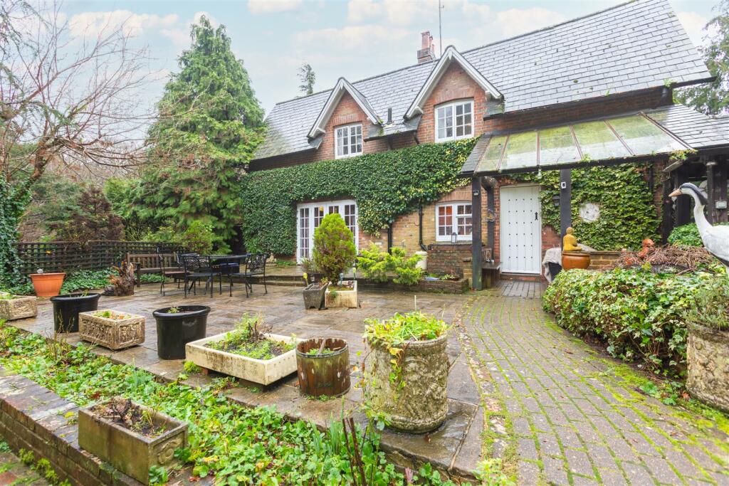 The ivy-clad cottage entrance with its glass porch and brick path