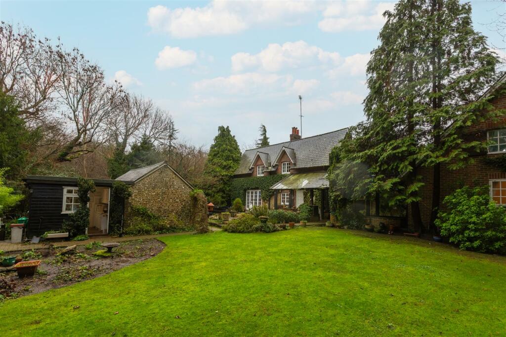 The sweeping garden lawn beside the flint outbuilding and cottage