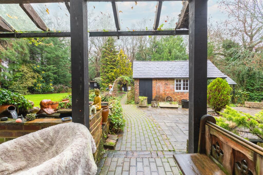 A view through the garden pergola towards the brick outbuilding